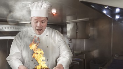 Ein Koch mit einem brennenden Topf