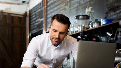 Ein Cafémitarbeiter tippt an seinem Laptop