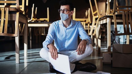 Junger Gastronom sitzt verzweifelt auf dem Boden seines Cafés