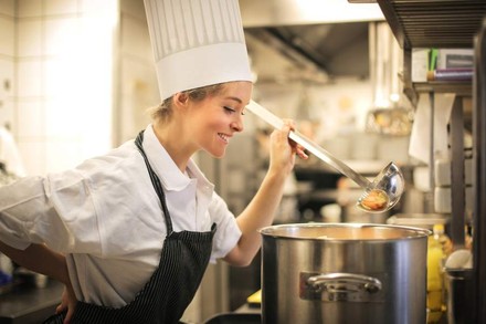 Eine Köchin blickt erfreut in einen Topf