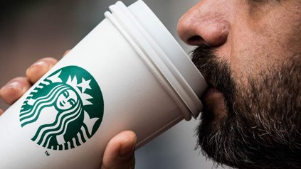 Ein Mann trinkt aus einem Starbucks Becher