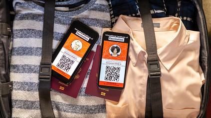 Gepackter Koffer in dem zwei Handy mit geöffnetem digitalen Impfpass liegen