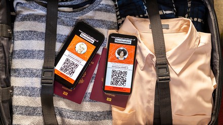 Gepackter Koffer in dem zwei Handy mit geöffnetem digitalen Impfpass liegen