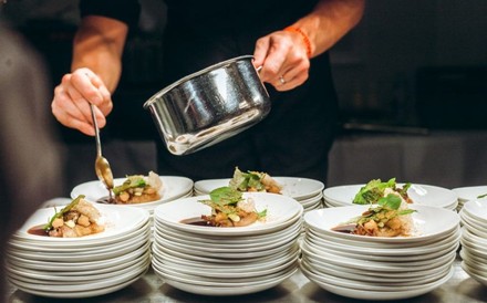 Ein Koch verteilt Soße auf Tellern mit Gerichten
