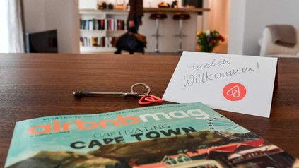 Ein Herzlich Willkommen-Schild, die Airbnbmag-Zeitschrift und ein Schlüssel liegen auf einem Tisch