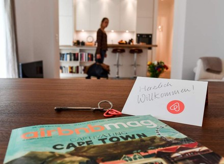 Ein Herzlich Willkommen-Schild, die Airbnbmag-Zeitschrift und ein Schlüssel liegen auf einem Tisch