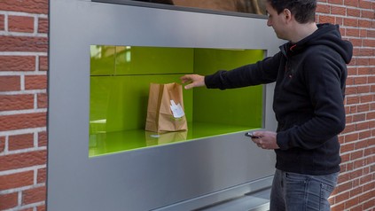 Mann entnimmt ein Packet am Ausgabeschalter einer Ghost Kitchen