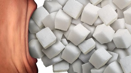 Person stopft sich viele Zuckerwürfel in den Mund