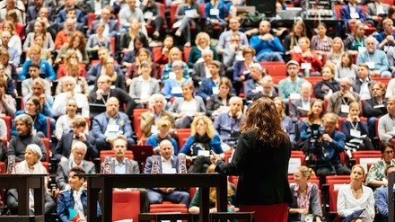 Frau steht in einem Vorlesungssaal der Leuphana Universität in Lüneburg vor dem Plenum und referiert