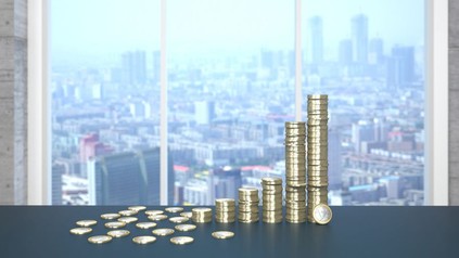 Einige Stapel Euromünzen vor einer Großstadtskyline