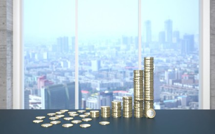 Einige Stapel Euromünzen vor einer Großstadtskyline