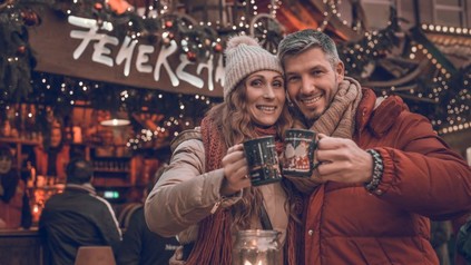 Paar mit Getränke-Häferln an einem Weihnachtsmarkt