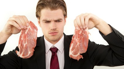 Mann betrachtet misstrauisch Fleisch in seiner Hand