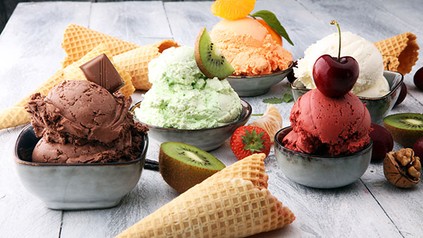 Diverse Eissorten in Schüsseln mit Obst und Waffeln