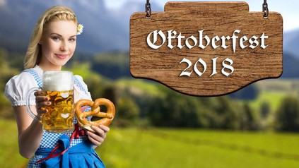 Eine Frau im Dirndl preist Bier und Brezen vor einem Schild mit der Aufschrift Oktoberfest 2018 an