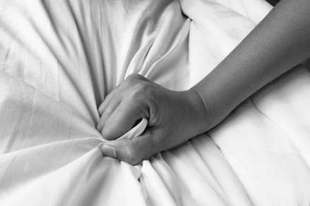 Hand greift in Bettlaken