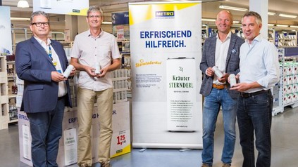 Christian Weber, Harald Jankovits, Arno Wohlfahrter und Michael Priessnitz stehen fröhlich vor einem Metro-Plakat