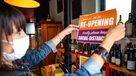 Frau hängt Geöffnet-Schild auf