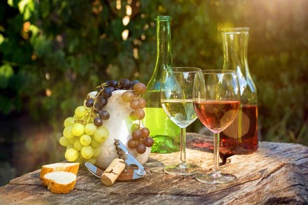 Weinflaschen, Weingläser und Trauben auf einem Tisch im Freien