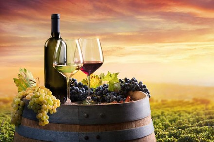 Zwei Weingläser und eine Weinflasche auf einem Holzfass