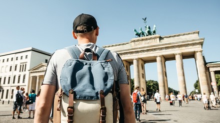 Ein Tourist mit Rucksack in Berlin besichtigt Sehenswürdigkeiten wie das Brandenburger Tor