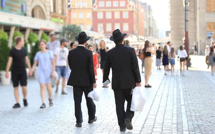 Zwei schwarz gekleidete Männder mit Hüten gehen eine Straße entlang