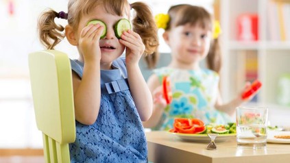 Ein Kind in einem Kindergarten mit Gurkenscheiben auf den Augen