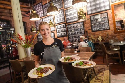 Eine lächelnde Kellnerin mit finnischen Gerichten auf Tellern