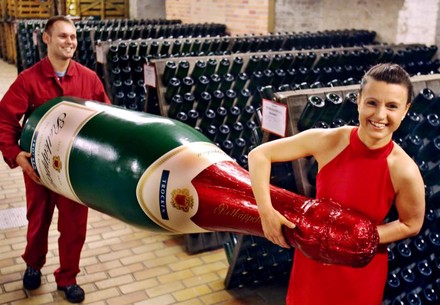 Zwei rot gekleidete Personen tragen eine riesige Rotkäppchenflasche