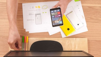 Mann vor PC Bildschirm mit Smartphone