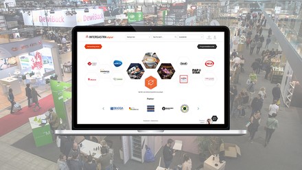 Aufgeklappter Laptop mit Aussteller-Logos der INTERGASTRA digital; im Hintergrund blass ein Blick in eine der Messehallen der Messe Stuttgart