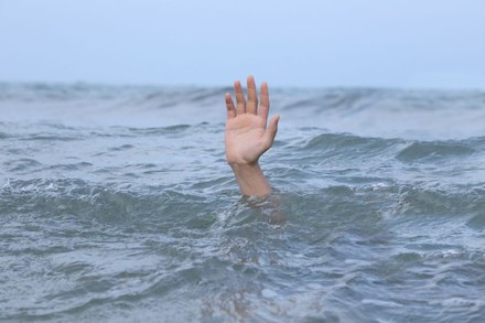 Person ertrinkt, Hand ragt aus Wasser