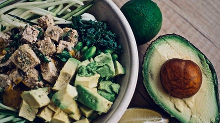 Tofu-Bowl mit hauptsächlich grünen Zutaten wie Avocado, Salat und Limetten