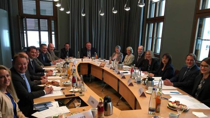 Eine Gruppe Menschen diskutiert lächelnd an einem großen Tisch