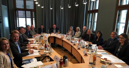 Eine Gruppe Menschen diskutiert lächelnd an einem großen Tisch