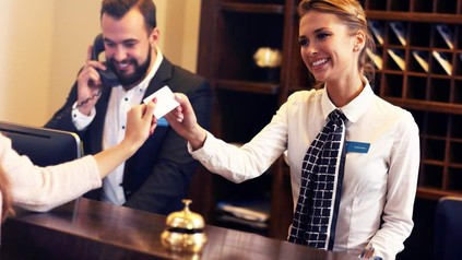 Zwei fröhliche Mitarbeiter an einer Hotelrezeption