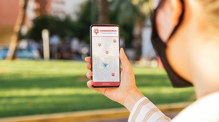 Eine junge Frau nutzt eine Corona-Tracking-App auf ihrem Smartphone