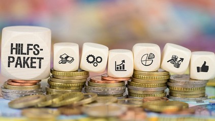 Würfel mit der Aufschrift Hilfspaket und Euro-Münzen