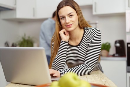 Frau sitzt mit Laptop am Esstisch