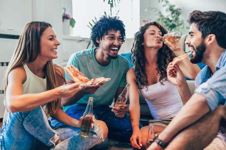 Vier Menschen lachen und essen zusammen