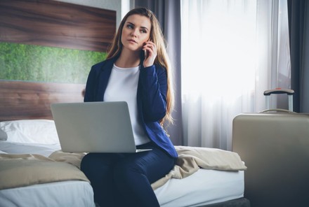 Geschäftsfrau auf Bett mit Laptop und Smartphone