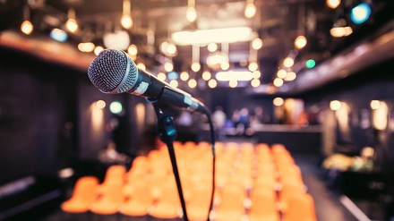 Ein Mikrofon auf einer leeren Bühne in einem leeren Veranstaltungssaal