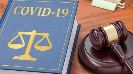 Buch mit der Aufschrift „Covid-19“ neben einem Richter-Hammer