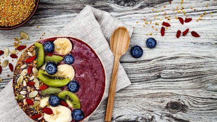 Eine farbenfrohe Schüssel gefüllt mit Körnern, Nüssen, Obst und lilanem Pürree