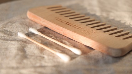 Ein Holzkamm und zwei biologisch abbaubare Wattestäbchen liegen auf einem Waschtisch