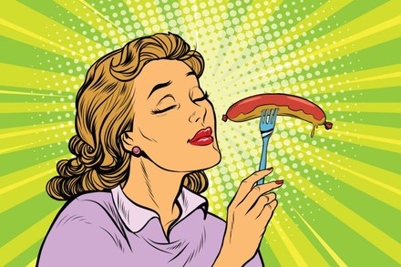 Frau riecht an Wurst auf Gabel