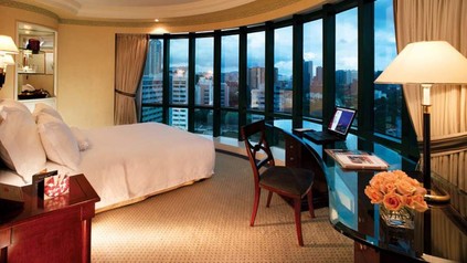 Ein modernes Hotelzimmer, dessen Bett vor einer Fensterfront steht