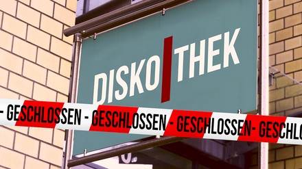 Diskothek-Schild und rot-weiß-gesteiftes Absperrband mit der Aufschrift „Geschlossen“