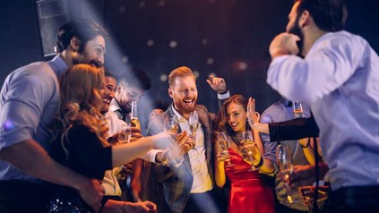 Junge fröhliche Menschen auf einer Ballermann-Party, die tanzen und Bier trinken.