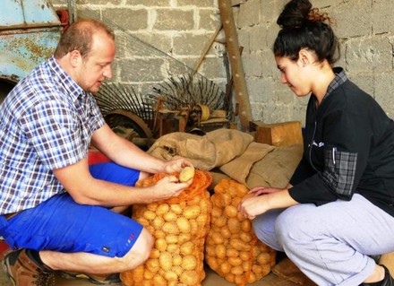 Uwe Steiniger und ein junges Mädchen öffnen zwei Säcke Kartoffeln
